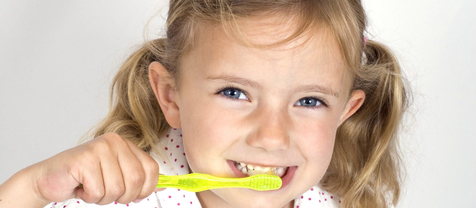 A little girl brushing her teeth with a brightly colored toothbrush