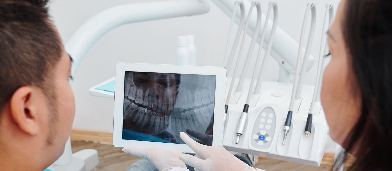 Orthodontist showing jaw x-ray to patient and telling what teeth should be treated or removed